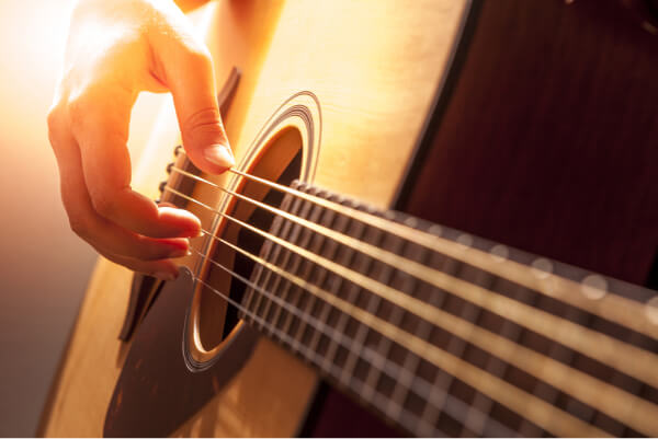 Una mano que toca las cuerdas de una guitarra criolla.