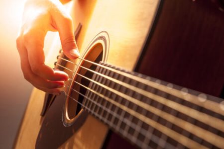 Una mano que toca las cuerdas de una guitarra criolla.